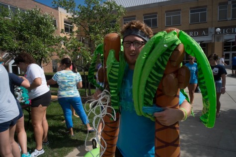 Student with two inflatable palm trees at the Beach Bash. 