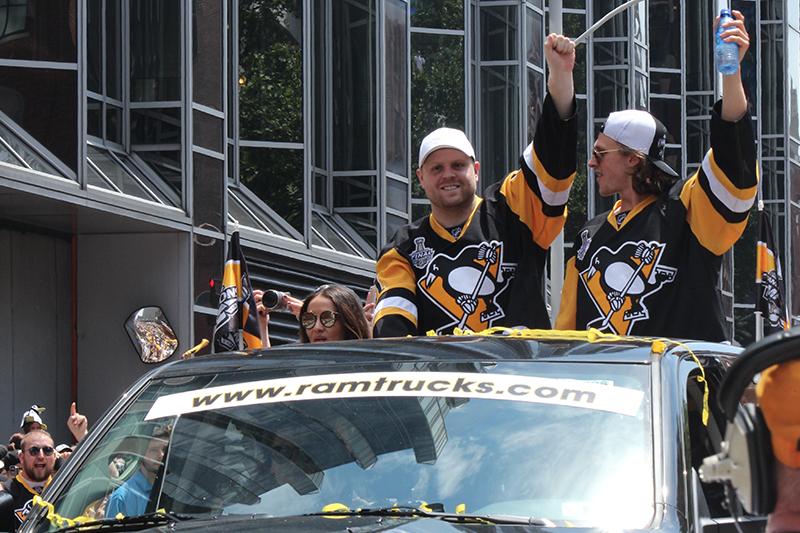 Phil Kessel (81) and Carl Hagelin (62) waves to the crowd as they ride down the Boulevard of the Allies.