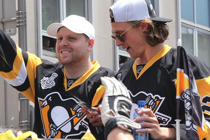 Phil Kessel waves to the crowd as Carl Hagelin (62) prepares to film the crowd.