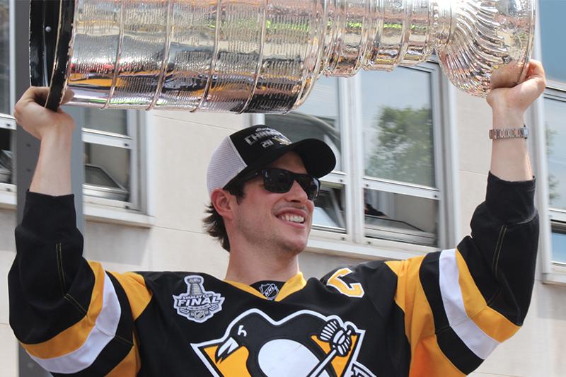 Sidney Crosby, the Conne Smythe trophy winner (playoff MVP), hoists the Stanley Cup above his head.