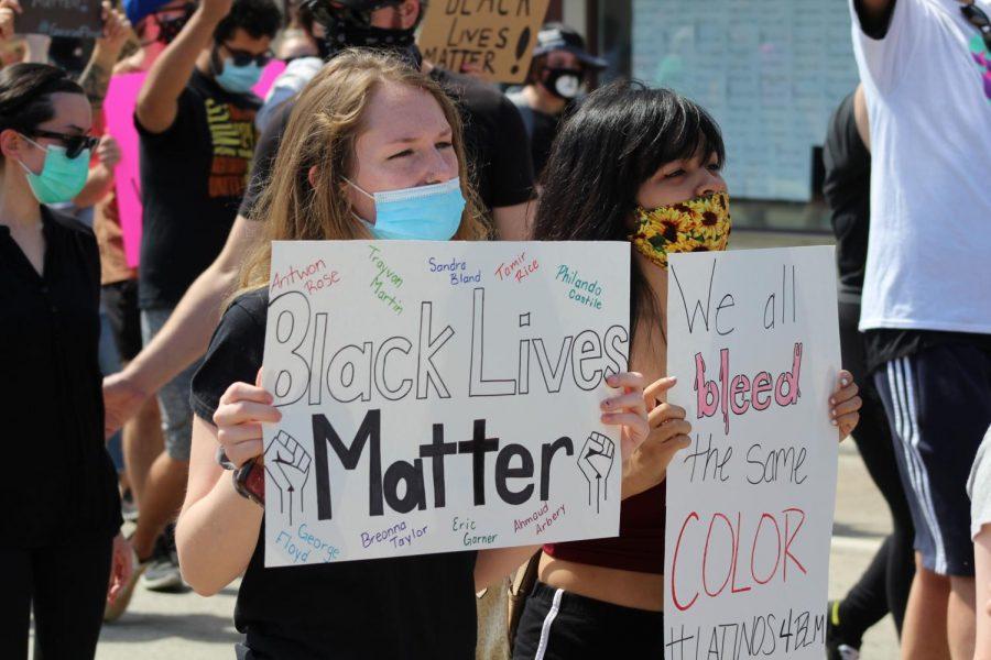 Two young protesters march together, with one sign reading #Latinos4BLM at the bottom. Coraopolis, PA. June 6, 2020. RMU Sentry Media/Garret Roberts 