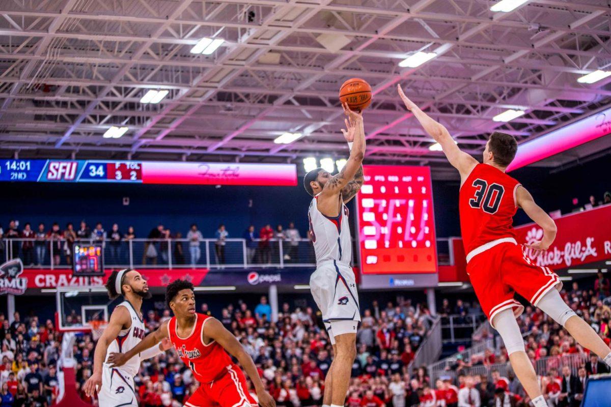 Deivydas Kuzavas (30) attempts to block an AJ Bramah shot in the Northeast Conference championship, the last time RMU faced Saint Francis. Photo Credit: David Auth