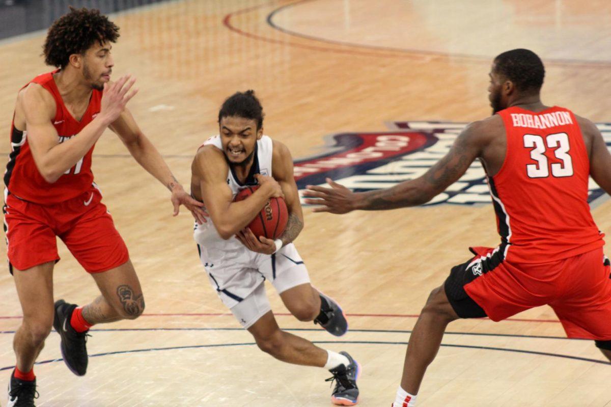 Trayden Williams maneuvers around Michael Akuchie and Naz Bohannon in the Colonials 70-66 overtime loss to Youngstown State on Saturday. Photo Credit: Ethan Morrison