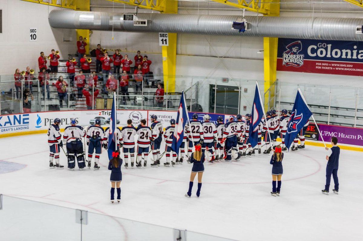 The hockey team listens to the RMU band play the alma mater after their game.
