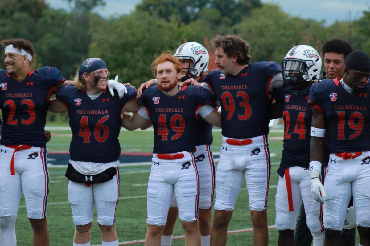 RMU football links arms after their win over Howard.